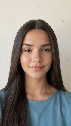 Young woman with long dark hair wearing a blue shirt, looking at the camera