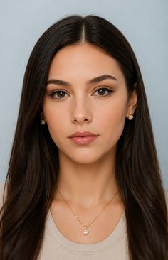 Woman with long dark hair wearing earrings and a necklace, looking directly at the camera