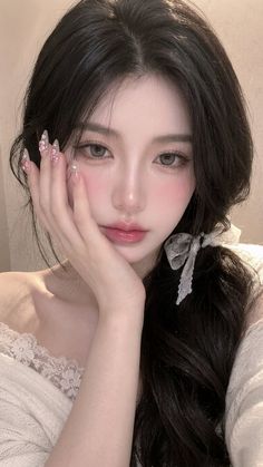 Woman with long black hair and a lace top, holding her hand to her face
