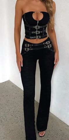 Woman in a black corset top and buckle pants standing indoors