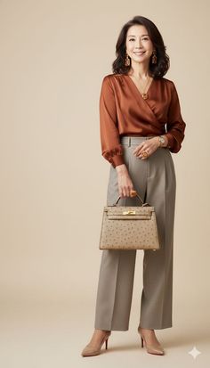 Woman in a brown blouse and wide-leg pants holding a handbag in a studio