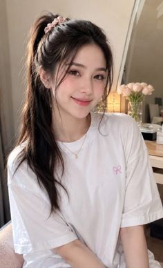 Woman with a ponytail and natural makeup wearing a white t-shirt indoors