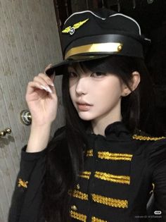 Person in a black pilot uniform with gold trim, holding their hat