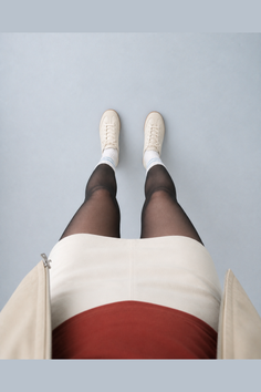 Person wearing black tights, white skirt, and white sneakers with blue striped socks