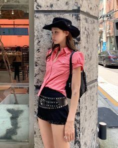Woman in a cowboy hat and plaid shirt with a studded belt on a street