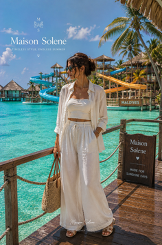 Woman in a white outfit standing on a wooden pier at a tropical resort