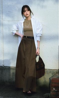 Woman in wide leg pants and a white shirt holding a fringe bag outdoors