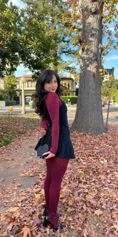 Woman in a black skirt and burgundy tights with a heart-shaped bag outdoors