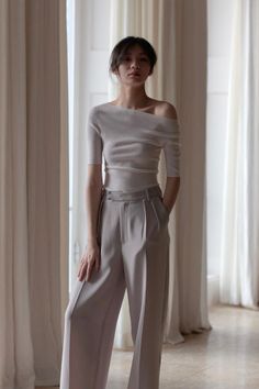 Woman in an off-shoulder top and wide-leg pants standing indoors