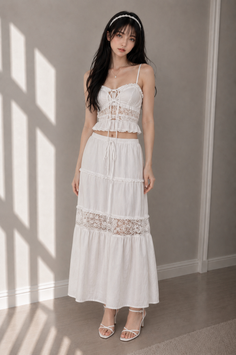 Woman in a white lace top and maxi skirt with a headband indoors