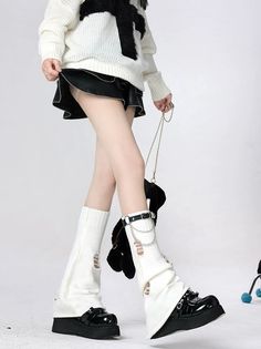 Person in a white sweater, black skirt, and leg warmers on a white background