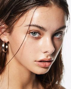 Woman with wet hair and blue eyes wearing hoop earrings, close up portrait