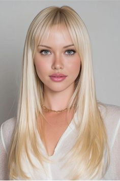 Woman with long blonde hair and blue eyes wearing a gold necklace and white shirt