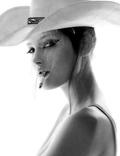 Woman in a cowboy hat smoking a cigarette in black and white