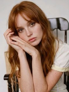 Woman with red hair and freckles resting her chin on her hands