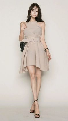 Woman in a beige dress and black high heels posing in a studio