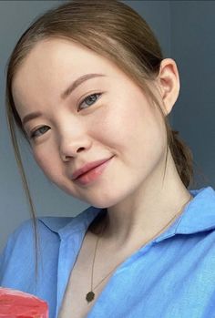 Woman with brown hair in a blue shirt and gold necklace