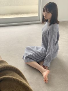 Woman with short hair in a ribbed dress sitting on the floor indoors