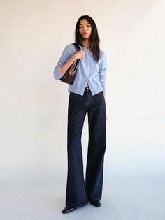 Woman with long hair wearing a light blue cardigan and wide leg jeans