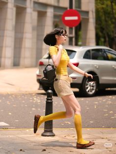 Woman in a yellow top and knitted skirt running on a sunny street