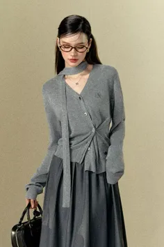 Woman with long hair and glasses wearing a gray cardigan and midi skirt