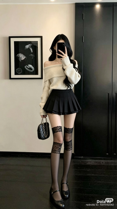 Woman in an off-shoulder sweater and pleated skirt taking a mirror selfie