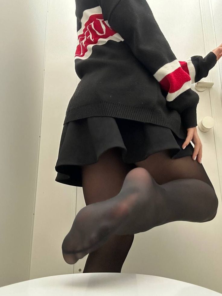 Person in a black sweater and mini skirt with one leg raised