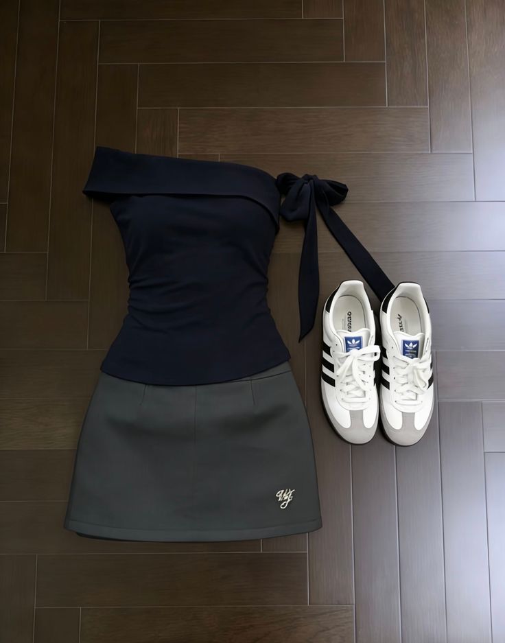 Off-shoulder top, mini skirt, and sneakers laid out on a wooden floor