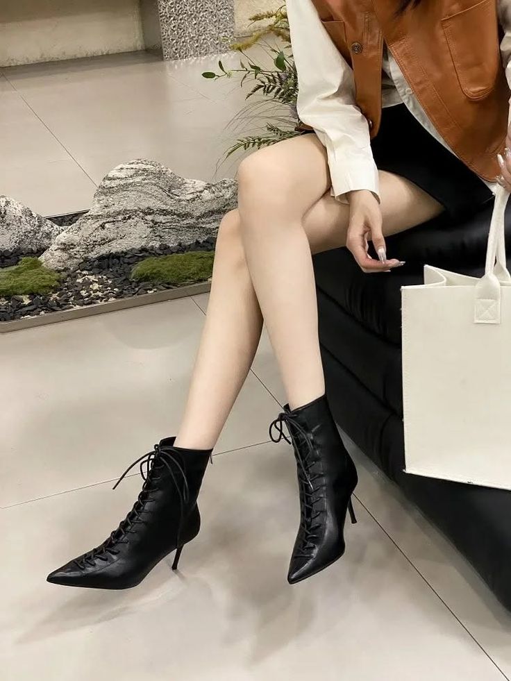 Woman wearing black lace-up boots and a short skirt, sitting indoors