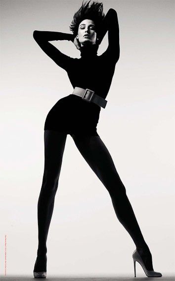 Woman in a black turtleneck and high heels posing in a studio