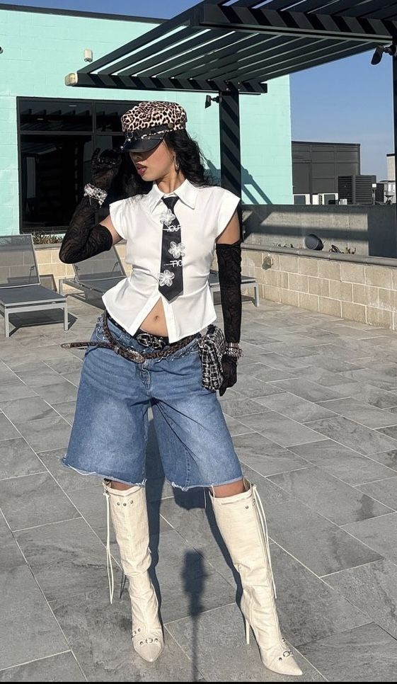 Woman in a leopard print hat, white shirt, denim shorts, and knee high boots outdoors
