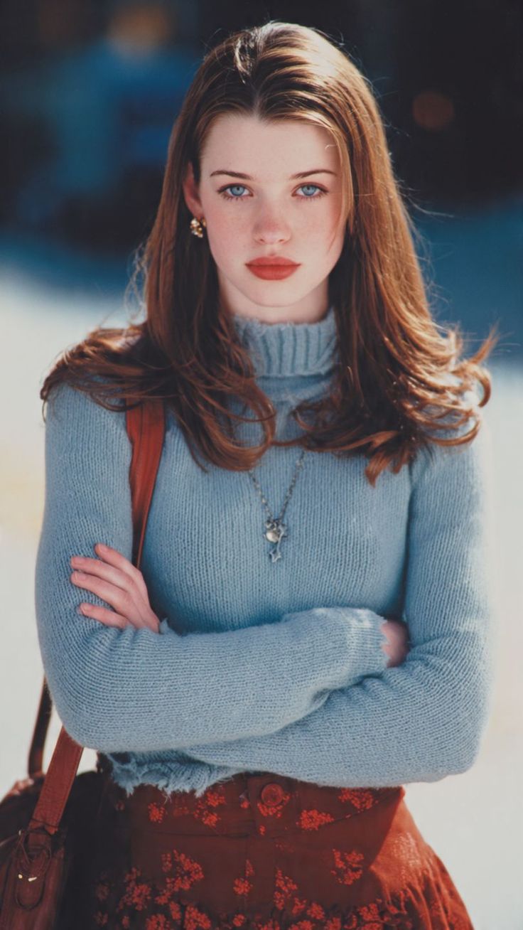 Woman with long brown hair and blue eyes wearing a blue turtleneck sweater