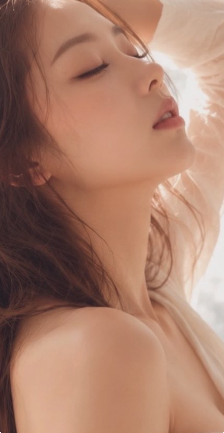 Woman with long hair and closed eyes, bathed in soft, warm backlight
