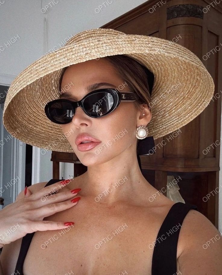 Woman in a straw hat and sunglasses with red nails and pearl earrings