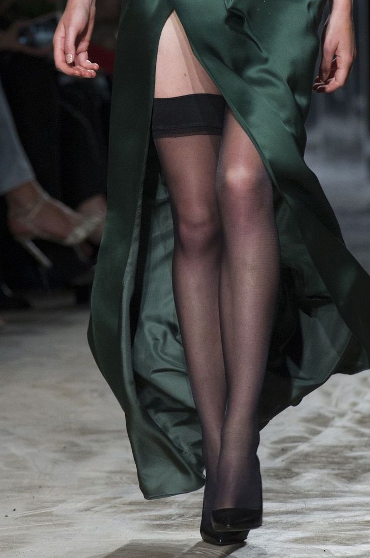 Woman in a green dress with a high slit and thigh-high stockings