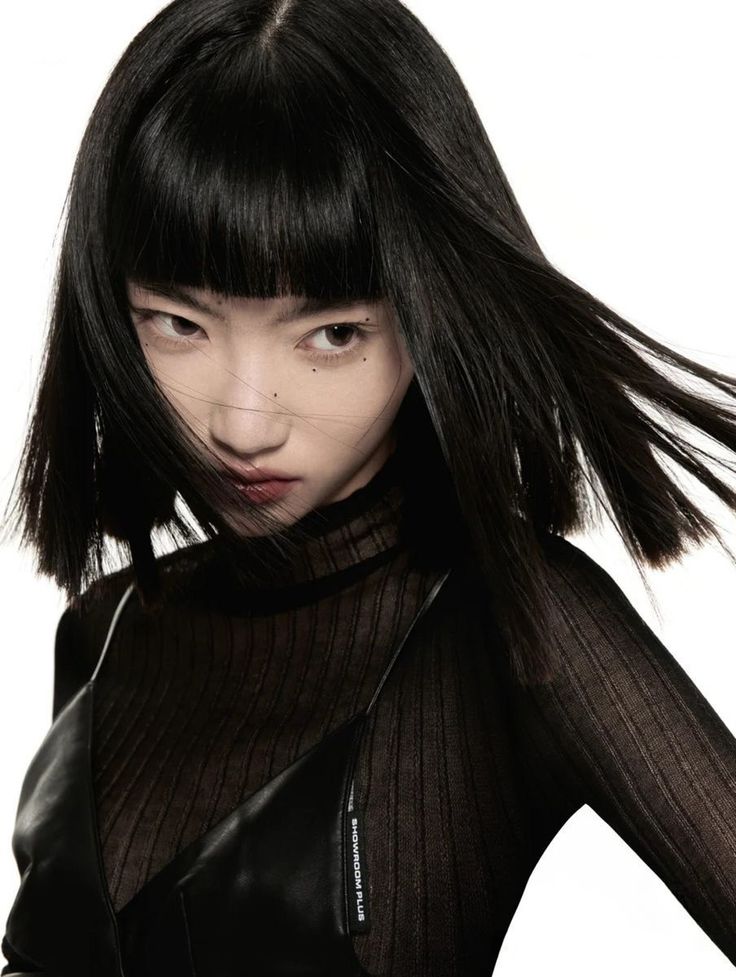 Woman with black hair and bangs wearing a sheer black top