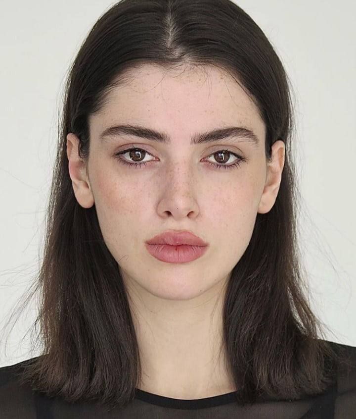 Woman with dark hair and freckles looking directly at the camera