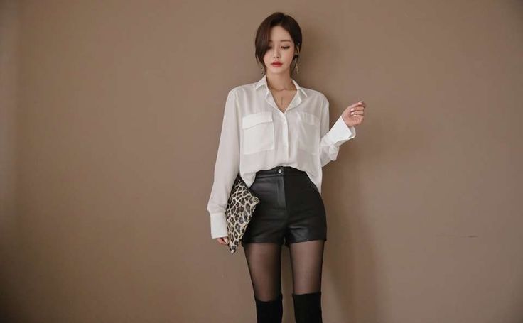 Woman in a white shirt and leather shorts holding a leopard print clutch