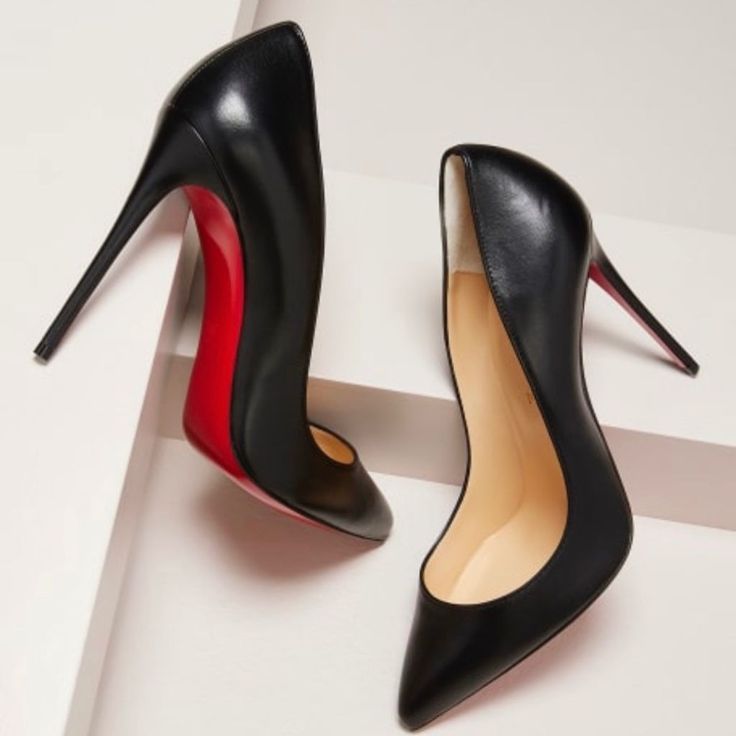 Pair of black high heels with red soles on a white background