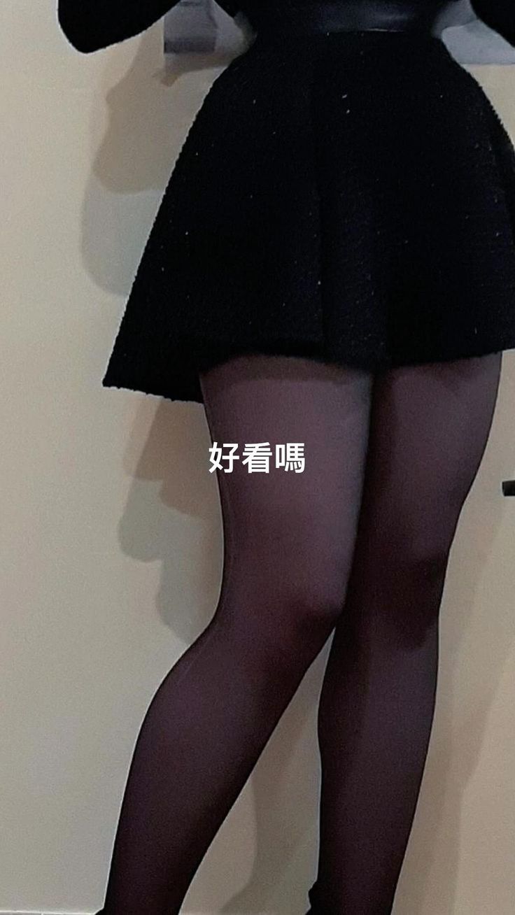 Person wearing a black skirt and tights, standing indoors