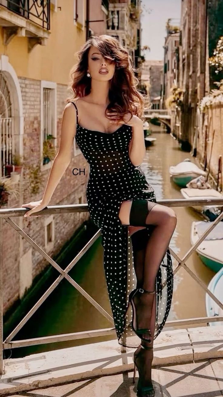 Woman in a polka dot dress and thigh-high stockings posing on a bridge over a canal