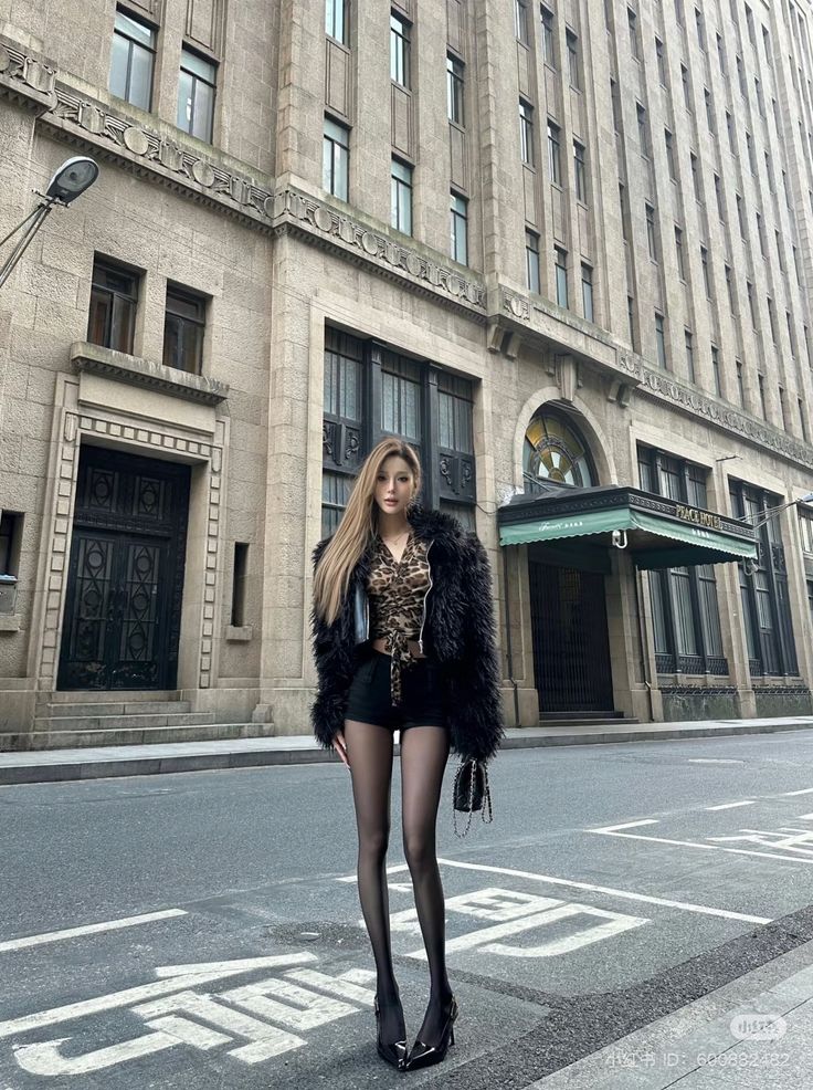 Woman in a black fur coat and leopard print top on a city street