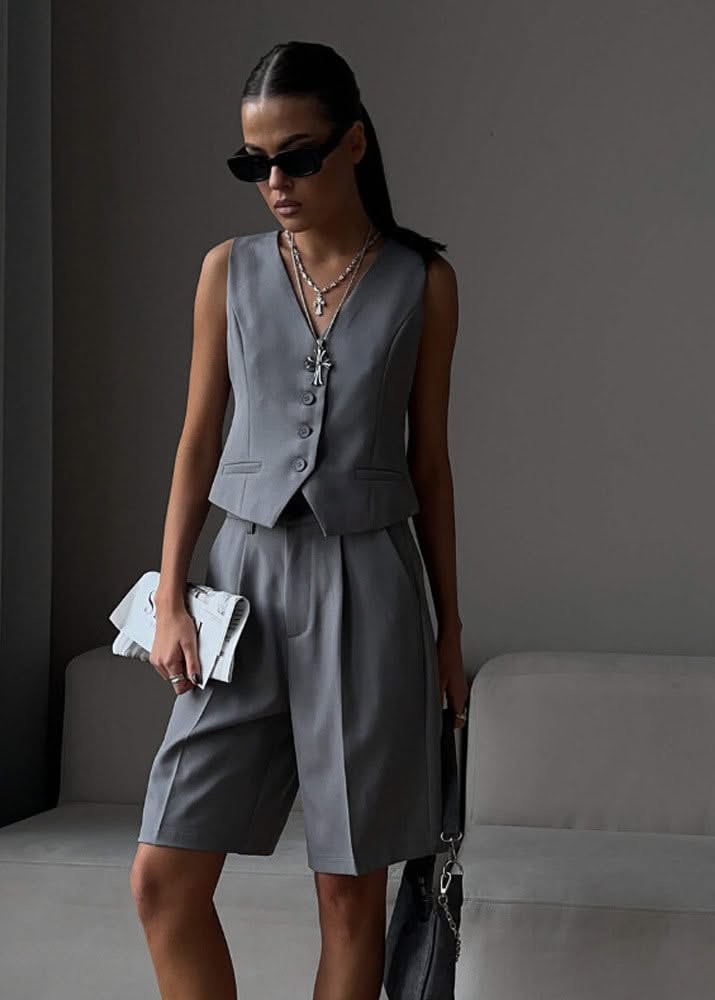 Woman in a gray vest and bermuda shorts with sunglasses and a ponytail