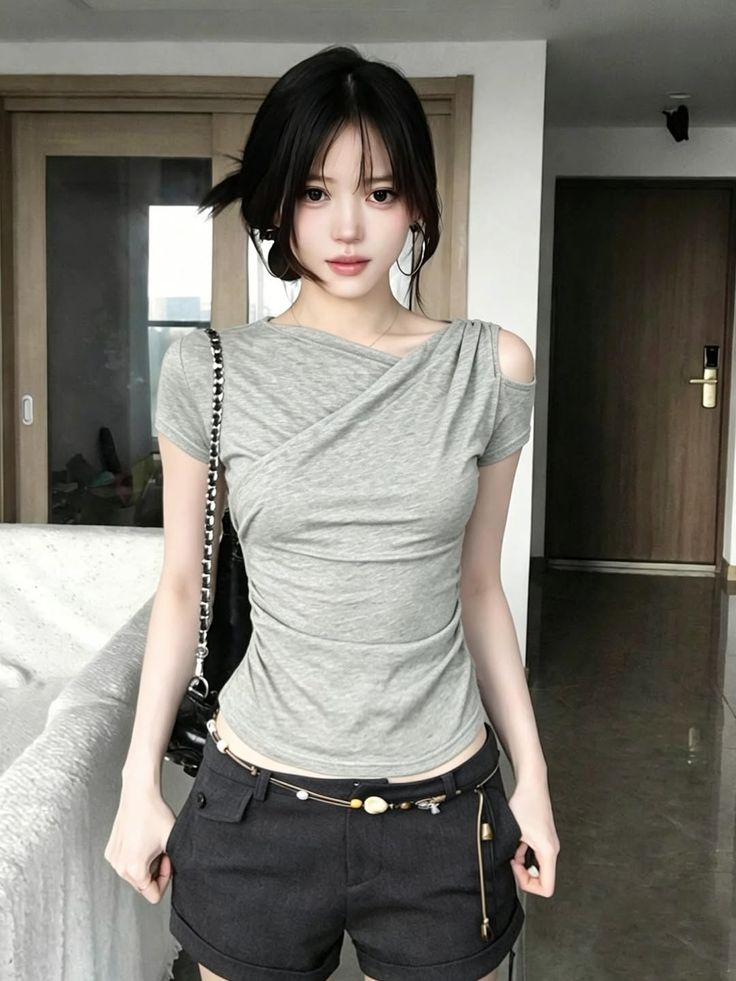 Woman with black hair wearing a gray top and shorts indoors