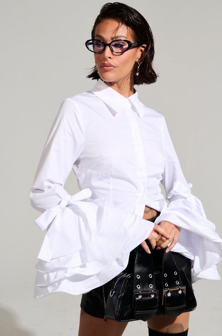 Woman in a white shirt with ruffle sleeves and black skirt in a studio