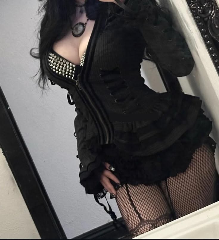 Woman in gothic attire with a studded bra and fishnet stockings