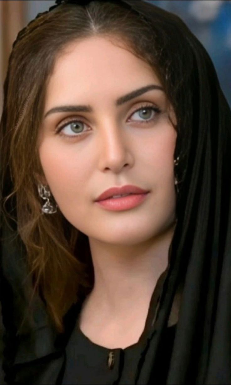 Woman with long hair and green eyes wearing a black headscarf