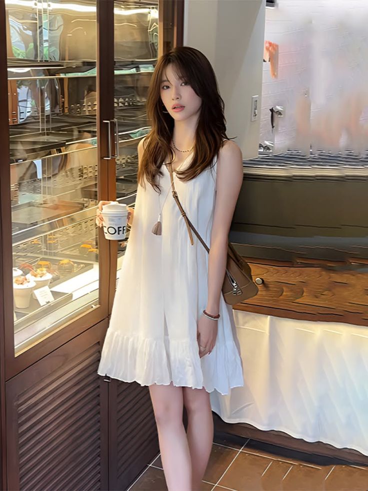 Woman in a white dress holding a coffee cup in a cafe