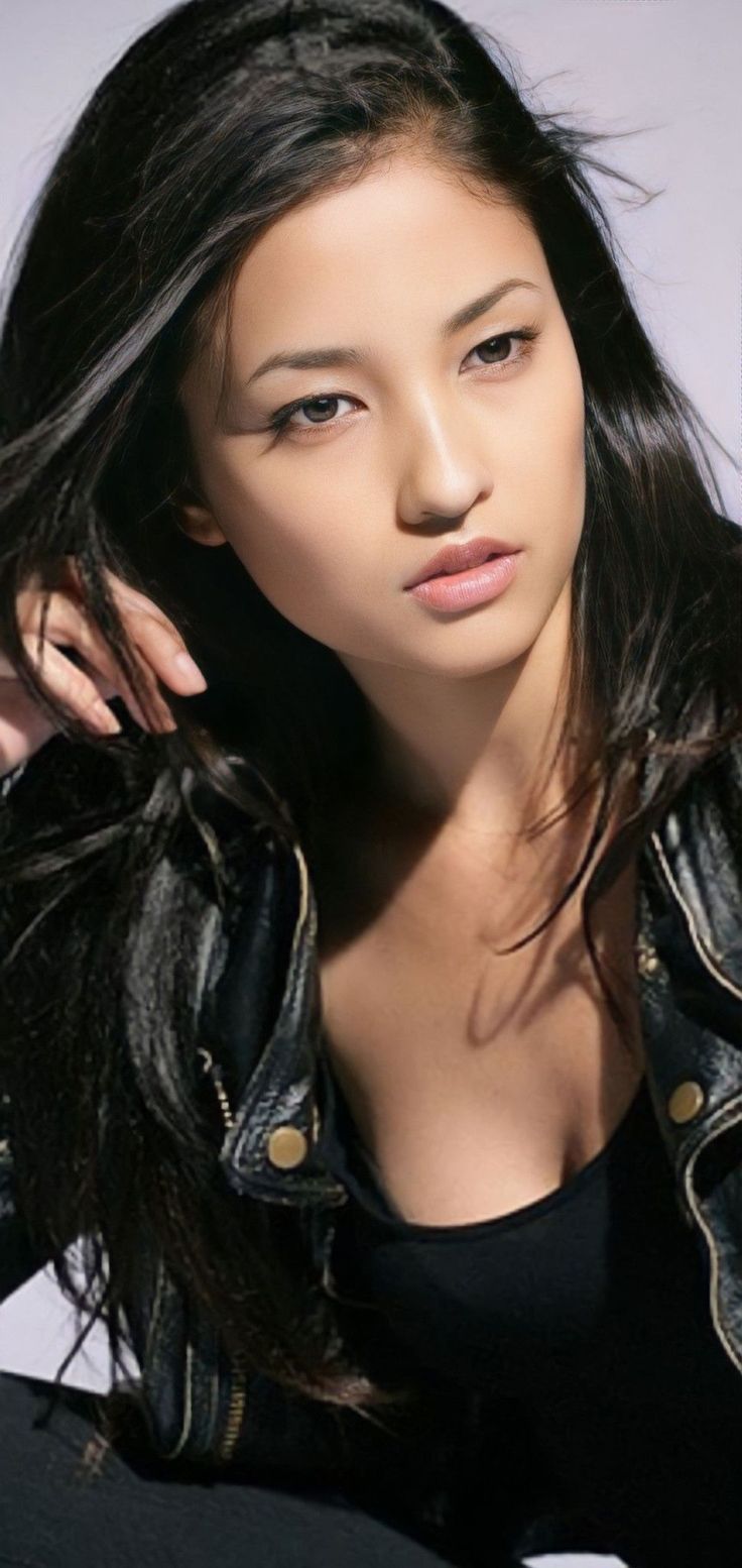 Woman with long black hair wearing a leather jacket and black top