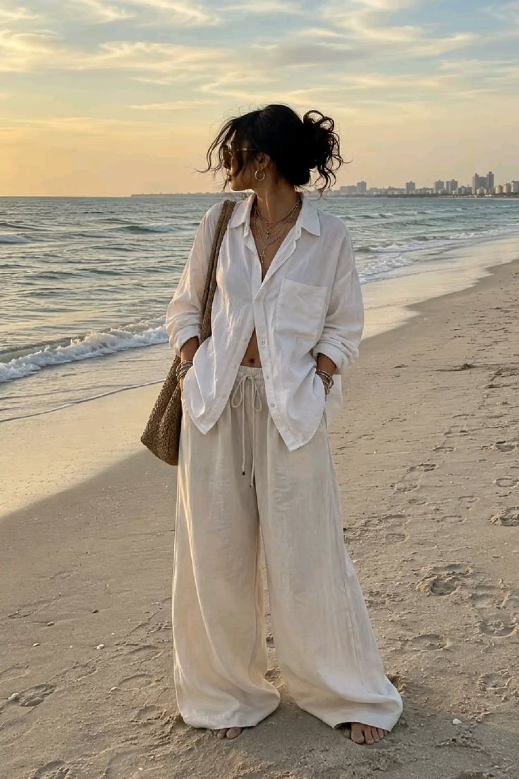 Woman in a white shirt and wide leg pants on a beach at golden hour